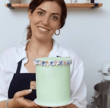 Ailu Castosa sosteniendo una torta verde con flores de azúcar